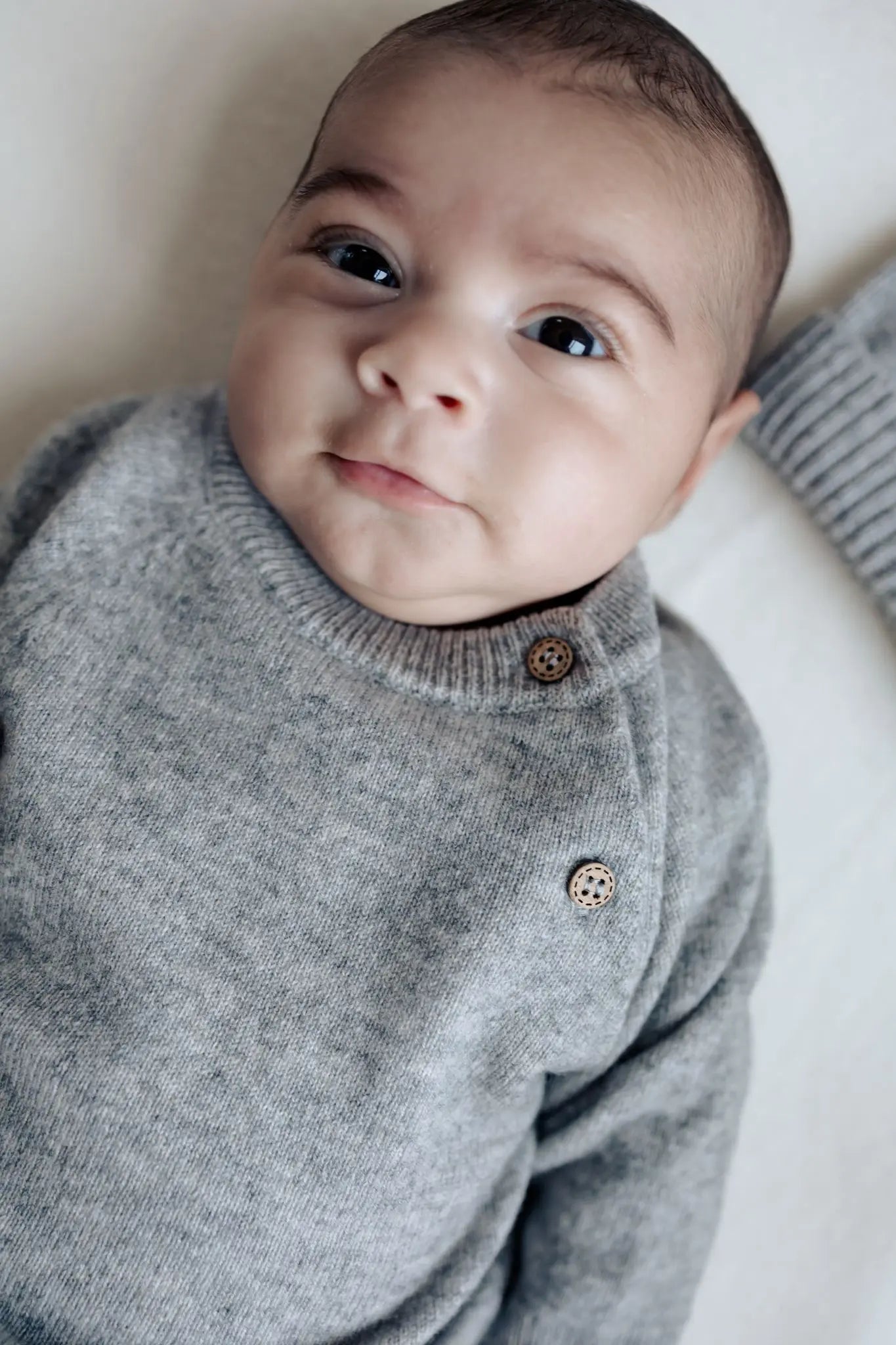 Close up van baby in grijs wollen truitje van Moalie