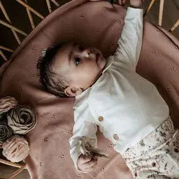 baby liggend op roze katoenen babydekentje – perfect voor de wieg