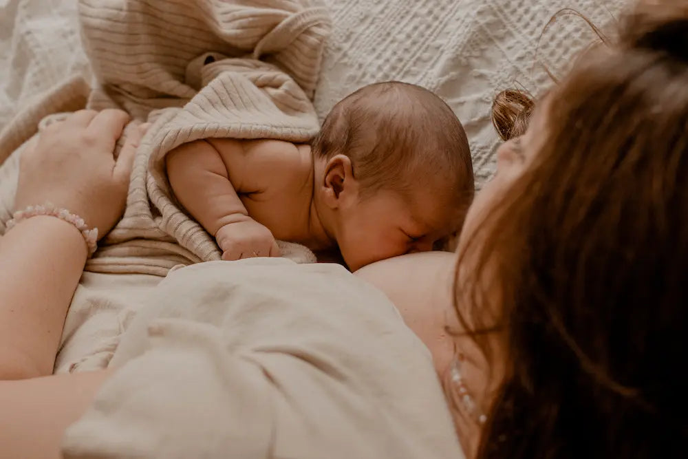 Baby krijgt borstvoeding en is toegedekt door merinowollen cocoon van Moalie 