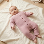 Baby in oud roze jumpsuit van gebreid katoen 
