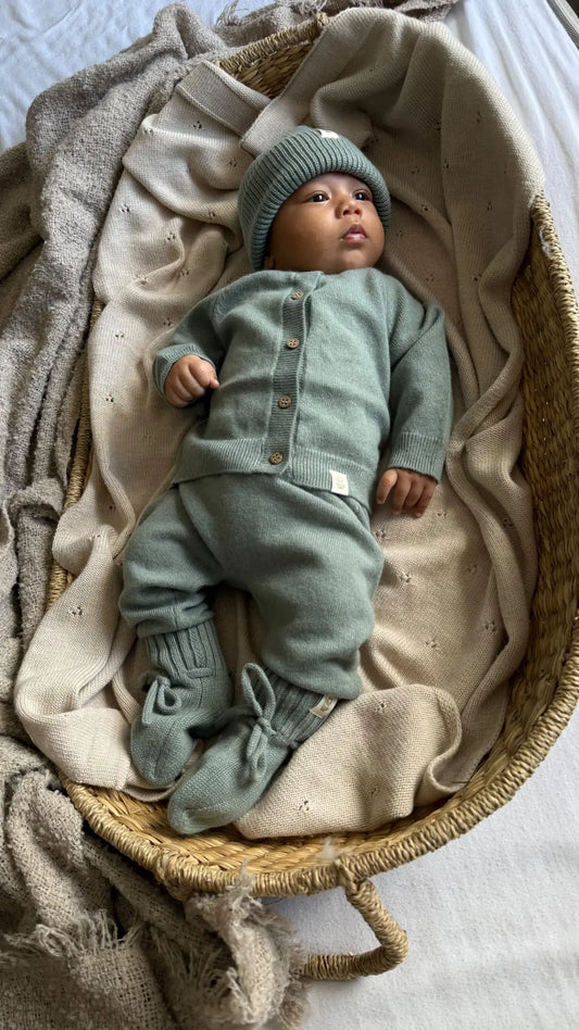 Baby in sage groene Moalie outfit van merinowol en cashmere