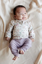 baby in Moalie setje bestaanden uit een lila broekje en gebloemde sweater