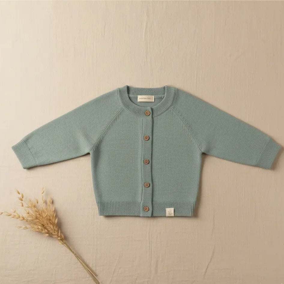 Baby vestje van merinowol en cashmere in Sage groen op een beige kleurige linnen achtergond 