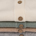 close up van een stapel baby vestjes van Moalie. Gemaakt van Merinowol en Cashmere met houten knoopjes 