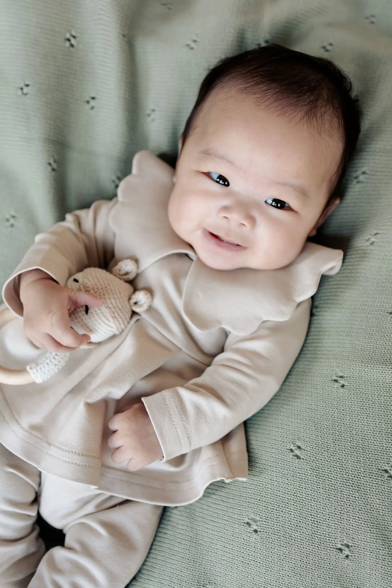 lachende baby in beige Moalie outfit 