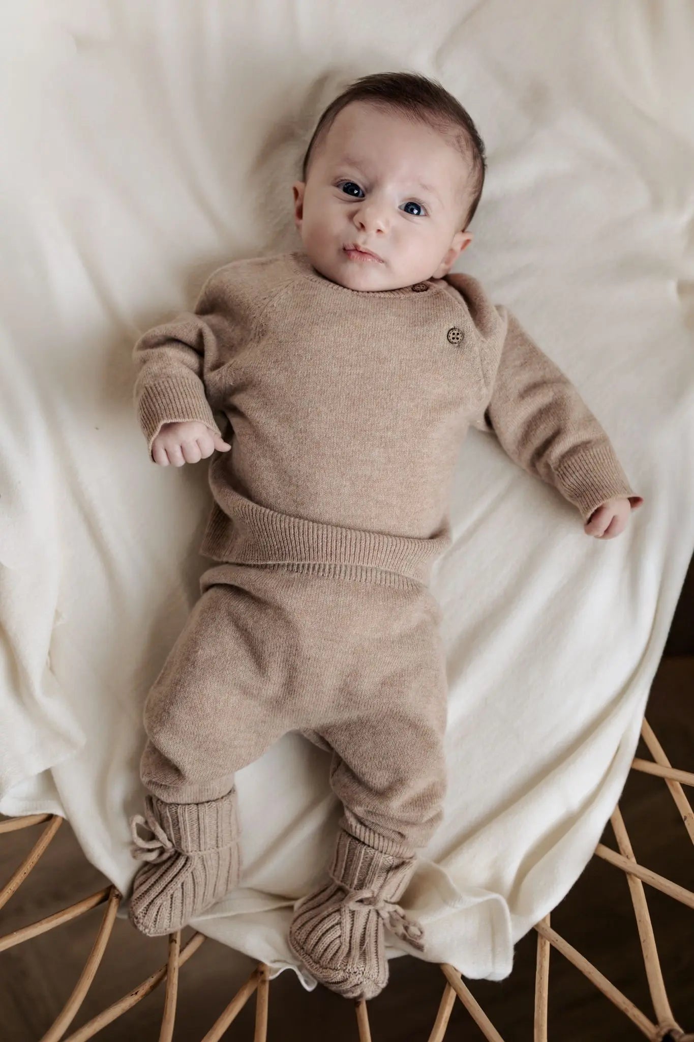 Baby in beige truitje, broekje en slofejs van merinowol en cashmere 