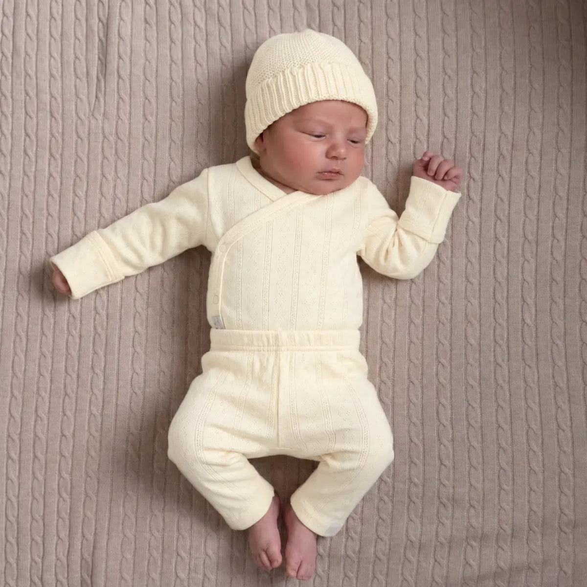Pasgeboren baby in  geboortepakje en katoenen babymuts in Buttercup Yellow