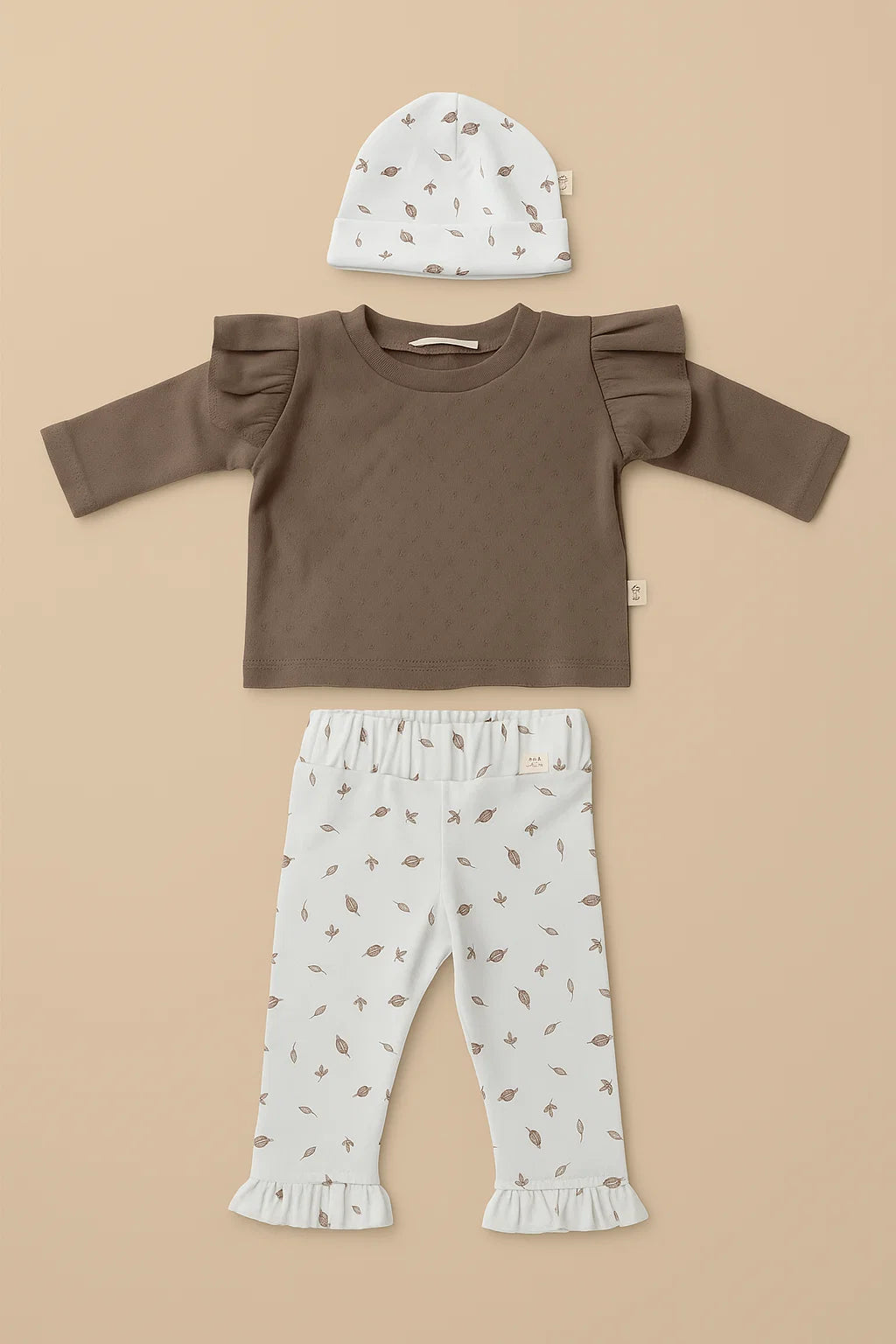 3 delig setje voor newborn baby. bestaande uit broekje met ruffle en newborn mutsje. Beide in witte stof met print van bruine blaadjes. Hierbij een bruine longsleeve, gemaakt van pointelle jersey en met ruffles op de schouders 