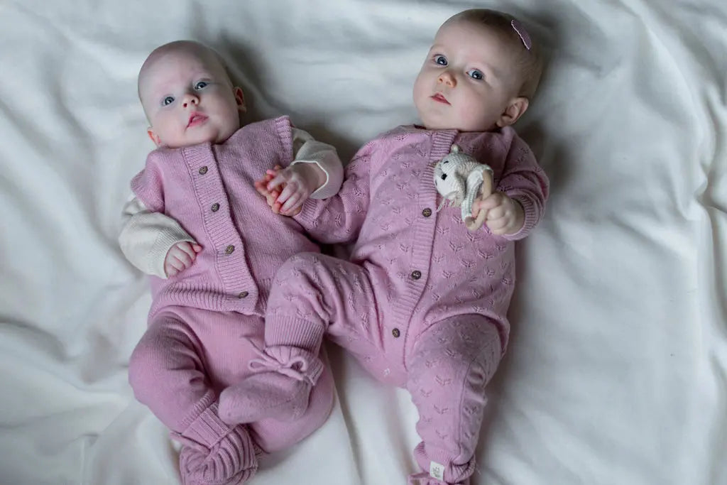 2 baby'is in roze wollen outfit. de baby rechts op de foto draagt een roze haarspeldje van krokodillenleer in roze lederlook