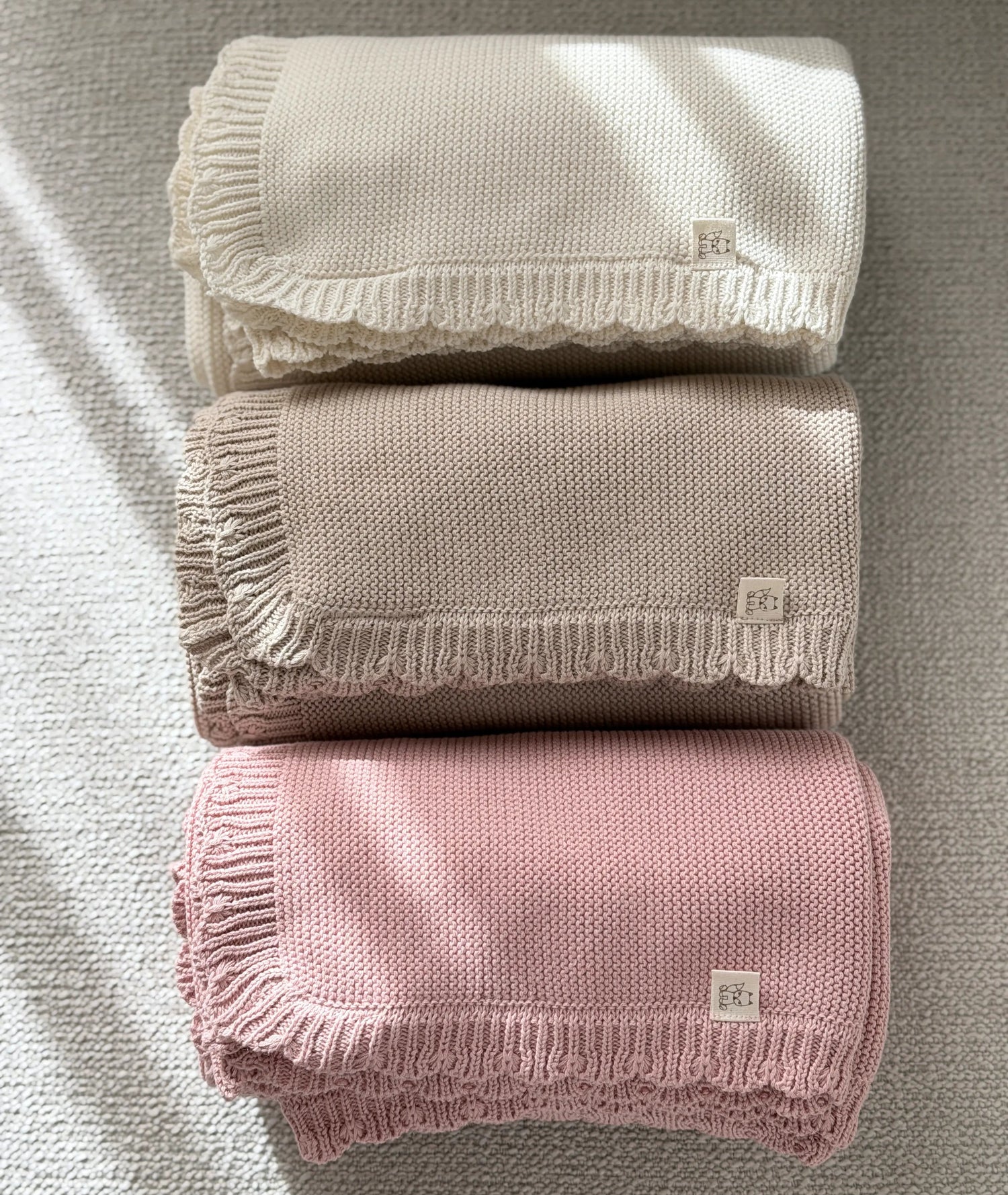 3 opgerolde katoenen babydekens met geschulpte rand in de kleuren off white, beige en roze 