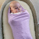 Baby in de Pointelle Snuggle Coco Lavender, een lila cocon van merinowol, in een rieten mandje