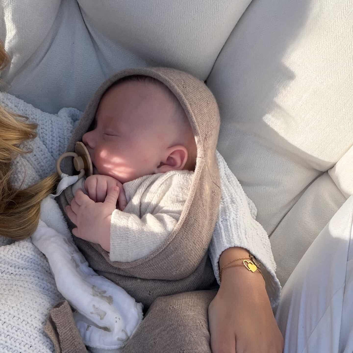 baby bij moeder op schoot slapend in camel kleurige merinowol baby cocon