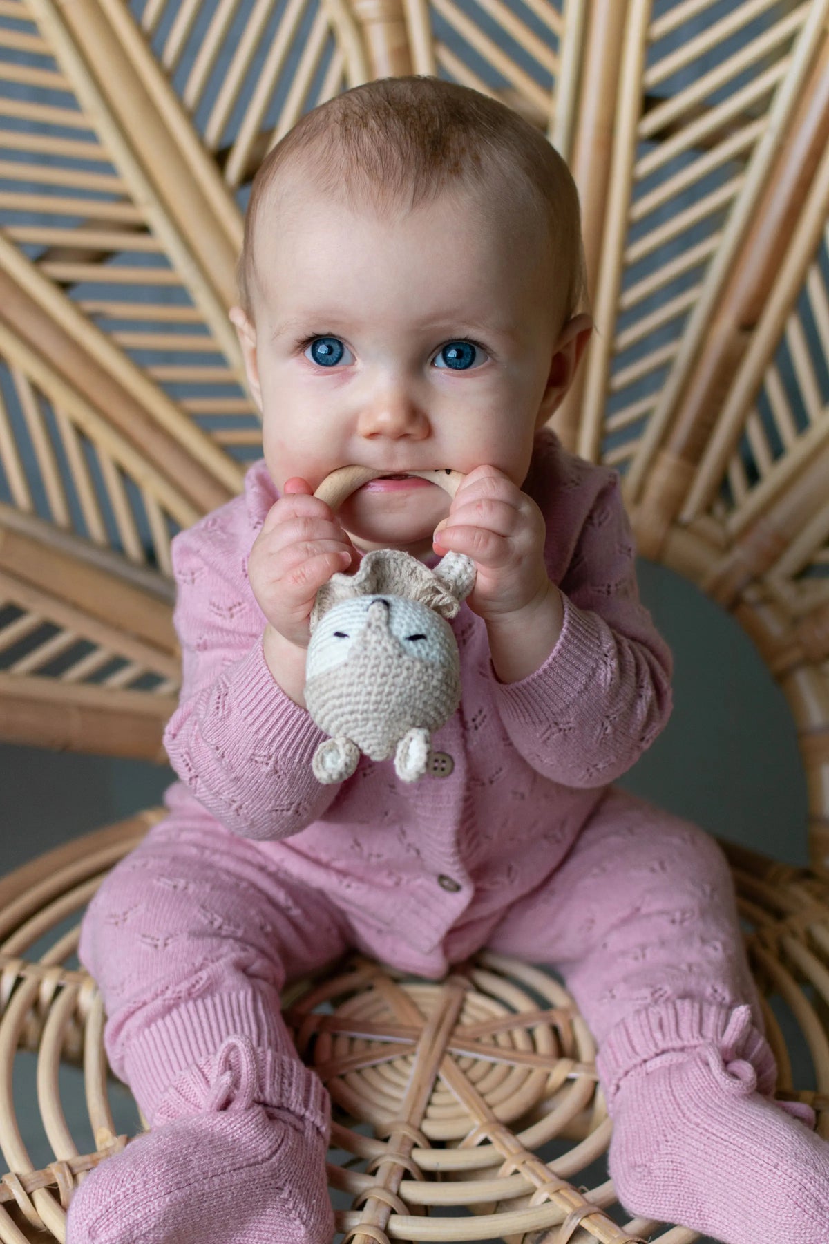baby op rotan stoel gekleed in een Merinowol/cashmere boxpakje en slofjes roze 