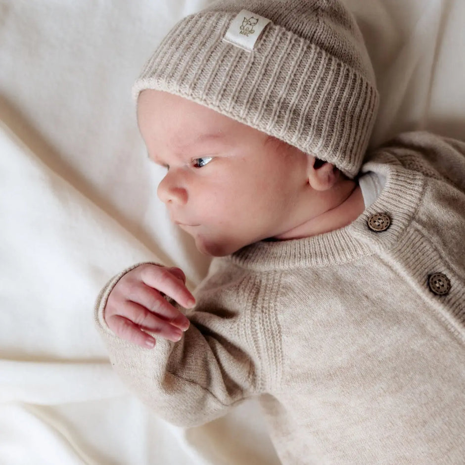 Baby in beiger Strickjacke aus Merinowolle