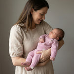 Mom holding her baby. The baby is wearing a knitted pink outfit made from merinowool and cashmere 