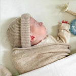Slapende baby in cocoon van beige merinowol