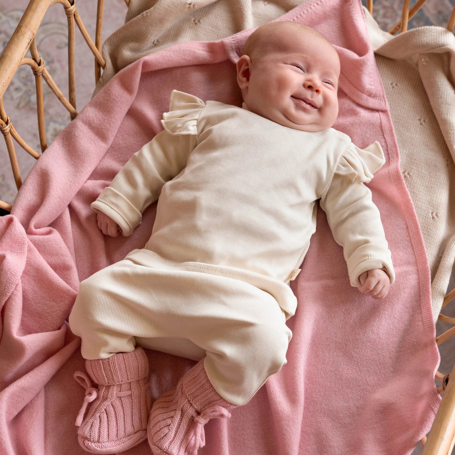 baby in Twee delig off white meisjes setje van biologisch katoen liggend op roze wollen deken
