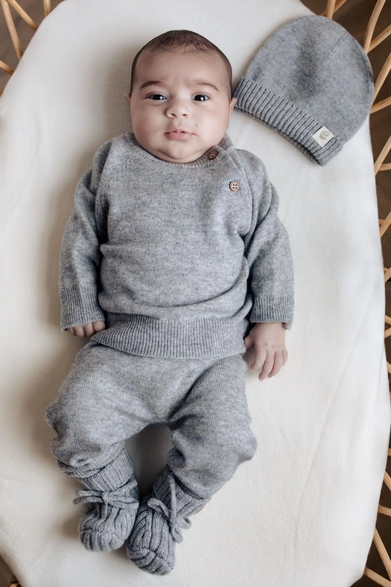 Baby in grijze merinowol en cashmere outfit van Moalie met bijapssende must en slofjes 
