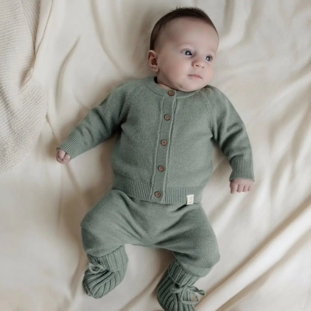Baby dressed in sage green merinowool and cashmere set. Cardigan, pants and booties 