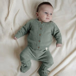 Baby dressed in sage green merinowool and cashmere set. Cardigan, pants and booties 