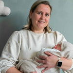 moeder met baby. de baby is gewikkeld in een zandkleurige merinowollen omslagdoek/ deken