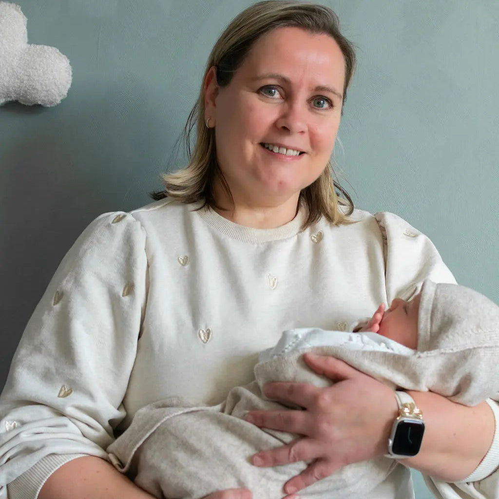 moeder met baby. de baby is gewikkeld in een zandkleurige merinowollen omslagdoek/ deken