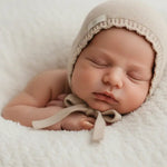 baby met merinowollen strik mutsje met geschulpte rand