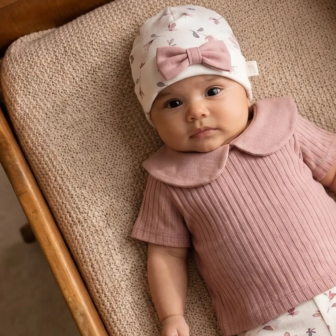 baby met gebloemd newborn mutsje Petal met oud roze linnen strikje 