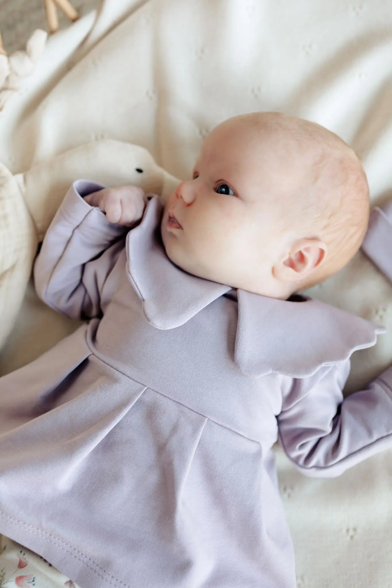 Baby op wollen deken met tuniek in lila 