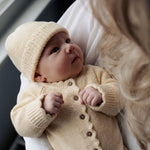 Newborn baby met katoenen babymuts Luna in Buttercup Yellow en bijpassend gebreid geboortepakje