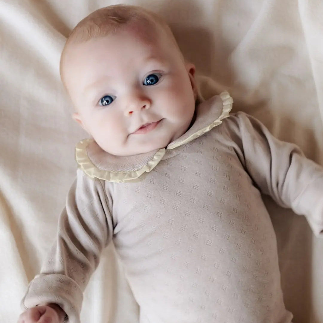 baby in beige pointelle romper met geschulpte kraag 
