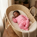 slapende  baby  in rieten mandje in een katoenen roze boxpakje