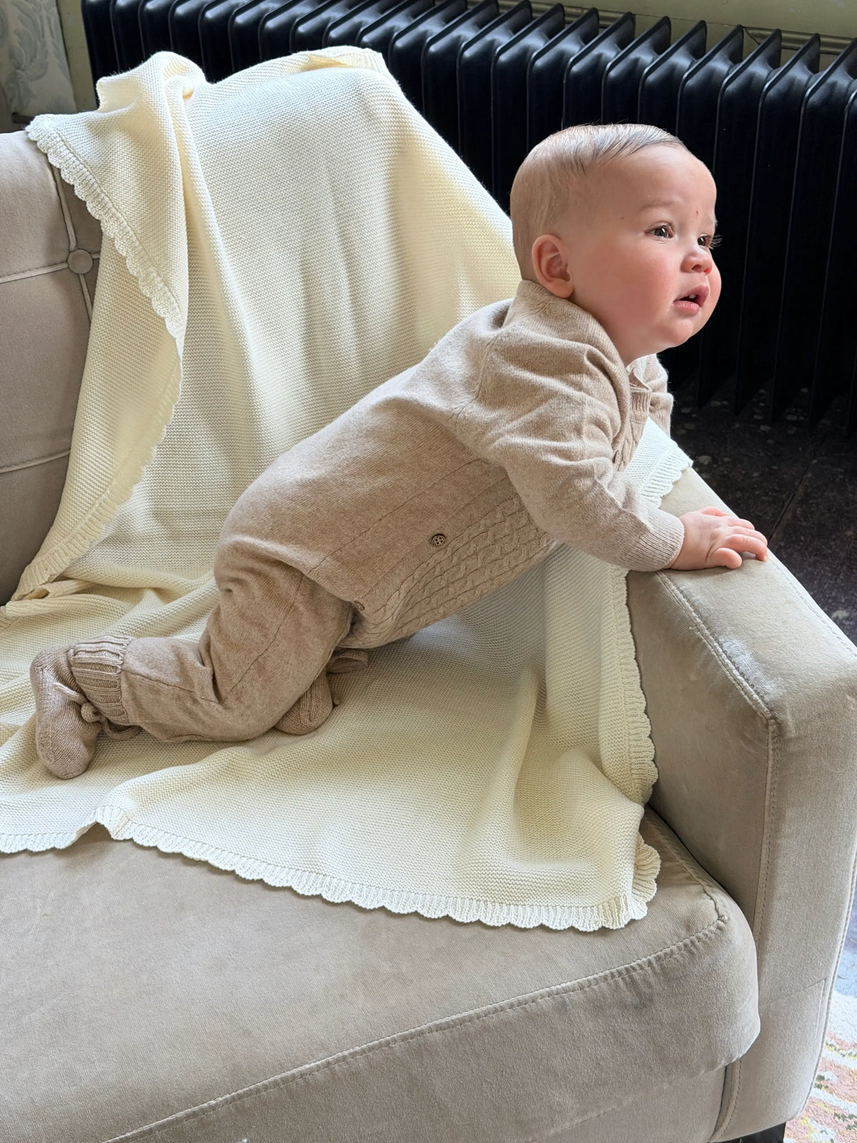 sfeerbeeld van baby op een stoel, zittend op zacht  gele kateonen deken mey schulprand 